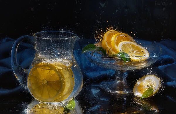 Jarros de água com rodelas de citrinos numa mesa iluminada